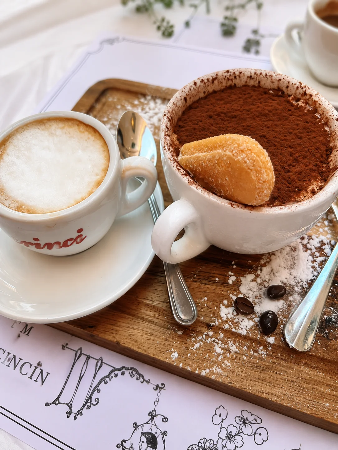 Coffee and a cocoa-topped dessert served on a wooden tray